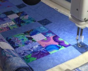 A lovely colourful quilt being quilted with popular baptist fan design