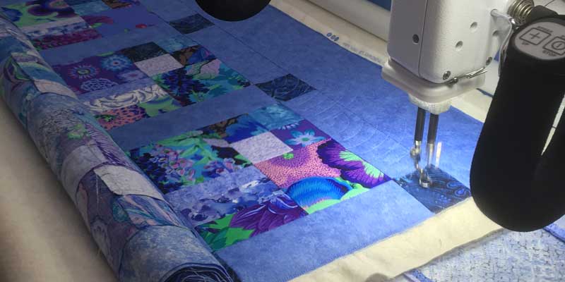 A lovely colourful quilt being quilted with popular baptist fan design