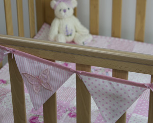 Applique embroidered butterfly bunting in pink on cot