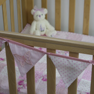 Applique embroidered butterfly bunting in pink on cot