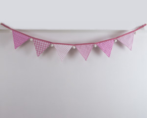 Baby pink bunting with white pom-poms front-on