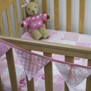 Ribbons and sequins bunting in pink on cot