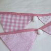 Baby pink bunting with whit pom-poms showing reverse